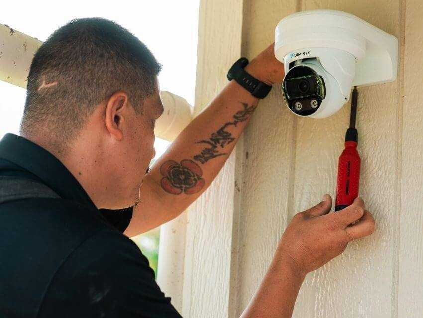 A  MPI employee installing a home security camera